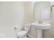 Powder room with modern toilet, pedestal sink, and decorative mirror at 6724 Seattle Slew Dr, Whitestown, IN 46075