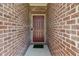 Close-up of the brick entryway with a solid red front door, and a small green welcome mat at 10890 Poppy Hill Dr, Indianapolis, IN 46234