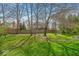 Spacious backyard with lush lawn, mature trees, and a fire pit area with seating at 11367 Zanardi Ct, Zionsville, IN 46077