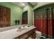 View of a bathroom with green walls, large mirror, and colorful shower curtain at 11691 Diamond Pointe Ct, Indianapolis, IN 46236