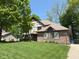 Two-story home featuring Tudor accents, brick facade, an American flag, and green lawn at 1728 Timber Heights Dr, Carmel, IN 46280