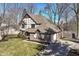 A Tudor-style home with brick and siding, a well-manicured lawn, and an attached garage at 1728 Timber Heights Dr, Carmel, IN 46280
