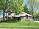 Beautiful Tudor-style home with green lawn and mature trees with a well manicured lawn at 1728 Timber Heights Dr, Carmel, IN 46280