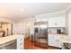 Bright kitchen features stainless steel refrigerator, white cabinetry, wood floor and eat-in counter at 1728 Timber Heights Dr, Carmel, IN 46280