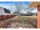 View of a fenced backyard with a brick house and a glimpse of surrounding neighborhood homes at 230 N School St, Fortville, IN 46040