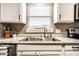 Close up of the kitchen sink with the window above with bright white cabinets and drawers at 3867 Asbury St, Indianapolis, IN 46227