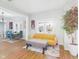 Sunlit living room featuring hardwood floors, a comfortable yellow sofa, and a charming view into the stylish dining area at 411 W Memorial Dr, Muncie, IN 47302
