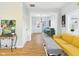 Open-concept living space with hardwood floors, a cheerful yellow sofa, and a view into the elegant dining area at 411 W Memorial Dr, Muncie, IN 47302
