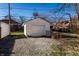 View of a detached one car garage with peeling white paint, gravel driveway, and wire fencing at 4929 Young Ave, Indianapolis, IN 46201