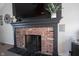 Close-up shot of a red brick fireplace with black accents and mantle at 6149 W Country Ln, Anderson, IN 46011