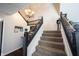Carpeted staircase featuring wooden railings and classic chandelier at 6149 W Country Ln, Anderson, IN 46011