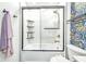 Shower/tub combination with sleek glass doors, tiled walls, built in shelving and decorative wallpaper at 629 Williamsburg Ln, Greenwood, IN 46142