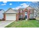 Charming two-story brick home boasts a manicured lawn, attached garage, and inviting blue front door at 6806 Powder Dr, Indianapolis, IN 46259