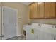 A functional laundry room equipped with cabinets, a utility sink, and laundry machines at 6806 Powder Dr, Indianapolis, IN 46259