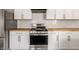 Close up shot of stainless gas range flanked by plentiful white cabinets and wood countertops at 706 N Euclid Ave, Indianapolis, IN 46201