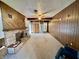 Spacious living room with a brick fireplace, wood paneling, neutral carpeting and a ceiling fan at 75 S 11Th Ave, Beech Grove, IN 46107