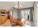 Bright dining area adjacent to kitchen with wood table set under a modern chandelier and natural light at 7899 S Timber Cliff Ln, Trafalgar, IN 46181