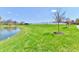 Scenic backyard view with lush green grass, a serene pond, and a white fence in the distance at 8630 Aylesworth Dr, Camby, IN 46113