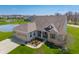 Aerial view showcases the brick home with a three car garage and pond in a beautiful community at 9559 Summer Hollow Dr, Fishers, IN 46037