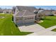 Aerial view of a brick fronted home with a three-car garage and a long driveway in a lush green neighborhood at 9559 Summer Hollow Dr, Fishers, IN 46037