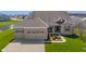 Beautiful brick home featuring a three-car garage, covered porch, and manicured lawn near a pond at 9559 Summer Hollow Dr, Fishers, IN 46037