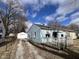 Cozy light blue home with a detached garage, gravel driveway, and small front porch at 1632 W 17Th St, Anderson, IN 46016