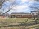 Expansive backyard features a brick home exterior, complemented by mature trees and a classic wooden swing set at 1840 Hibiscus Dr, Indianapolis, IN 46219