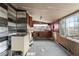 Dated kitchen featuring wood-paneled walls, a large window, and outmoded cabinets at 2123 N F St, Elwood, IN 46036