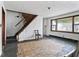 Room with staircase, large window, and damaged flooring at 2123 N F St, Elwood, IN 46036