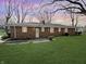 Brick ranch home with a well-maintained backyard and mature trees at dusk at 3008 Nichol Ave, Anderson, IN 46011