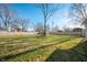 Expansive backyard with lush lawn, wooden fence, mature trees, and playset at 3225 S Rybolt Ave, Indianapolis, IN 46221