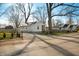 Street view of the home with gravel driveway, small fence and mature trees at 3225 S Rybolt Ave, Indianapolis, IN 46221