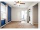 Bright living room features blue accent wall, neutral carpet, ceiling fan and a window at 3225 S Rybolt Ave, Indianapolis, IN 46221