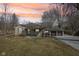 Charming single-story home featuring a covered porch and a detached two-car garage, set against a vibrant sunset sky at 4709 S County Road 500 E, Plainfield, IN 46168