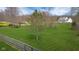 Lush green backyard featuring a charming house with a well-maintained lawn, mature trees, and a wooden fence at 4965 N 500 W, Columbus, IN 47201