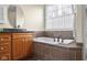 Bathroom featuring a soaking tub with brown tile, granite vanity, and a large window view at 4965 N 500 W, Columbus, IN 47201
