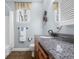 Bathroom features a granite countertop, round mirror, wooden cabinets, and a window at 4965 N 500 W, Columbus, IN 47201