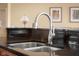 Close-up on a stainless steel kitchen sink with a modern faucet, set against dark countertops and custom cabinetry at 4965 N 500 W, Columbus, IN 47201