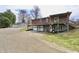 View of the brick home's back with an open wood deck, covered parking, and a two-car garage at 6900 W Georgetown Rd, Columbus, IN 47201