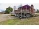 View of the brick home's back with an open wood deck, covered parking, and a two-car garage at 6900 W Georgetown Rd, Columbus, IN 47201