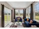 Bright sunroom with many windows, stylish curtains, comfortable seating, and sliding glass door access to the outdoors at 7326 Wooden Grange Dr, Indianapolis, IN 46259