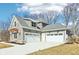 Exterior view showcasing the home's three-car garage with white doors and gray siding at 10756 Dartmoor Way, Zionsville, IN 46077