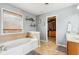 Bathroom featuring a jacuzzi tub, tiled floor, a window with blinds, and an open doorway to a walk-in closet at 12121 N Berling Dr, Mooresville, IN 46158