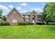 Beautiful two-story brick home featuring manicured landscaping and a lush green lawn on a sunny day at 12307 Pebblepointe Pass, Carmel, IN 46033