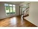 Bright living room with hardwood floors and large windows showcasing the natural light and staircase in the foyer at 12307 Pebblepointe Pass, Carmel, IN 46033