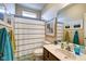 Well-lit bathroom with a striped shower curtain, decorative mirror, and a sink with cabinet storage at 1591 W 151St St, Westfield, IN 46074