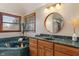 A luxurious bathroom featuring a green marble-clad soaking tub and vanity with a stylish round mirror at 5517 Westbourne Ct, Greenwood, IN 46143