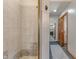 A walk-in shower featuring beige tiles, bronze trim, and an open doorway to a neighboring bathroom at 5517 Westbourne Ct, Greenwood, IN 46143