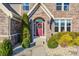 Charming brick home entrance with a red door, decorative wreath, and manicured landscaping at 5842 Oakmont Blvd, Bargersville, IN 46106