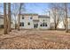 Exterior rear view of home with a patio, large yard, mature trees, and lawn covered in leaves at 6144 Maple Branch Pl, Indianapolis, IN 46221